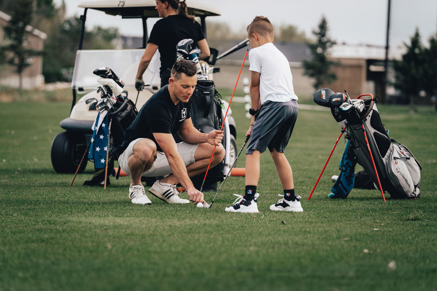 A Tee Box employee working with a group of kids on a golf course in Uintah, UT.
